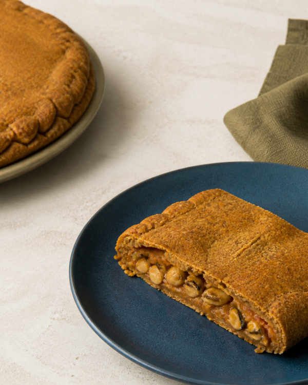 Empanada de millo con berberechos sobre un plato azul atlántico